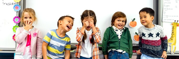 Poster - Group of diverse children laughing in a classroom. Kids smiling, having fun, and enjoying time together. Happy children, joyful classroom, diverse group. Cute little children in school.
