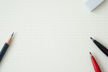 Wall Mural - top view, close-up of red and black felt-tip pen, pencil and eraser on graph paper background, copy 