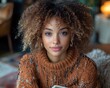 © Toya - Young woman with curly hair in cozy sweater reading a book indoors, warm ambiance