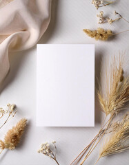 Poster - White blank card rests on a textured surface. Dry flowers and soft fabric create a natural, calm scene. Simple invitation sits among the organic elements, creating a neutral background.