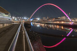 Nightscape view of The Iconic gateshead millennium bridge with Tyne bridge and dark sky in the background. The pedestrian bridge spanning the River tyne with reflection in river, Space for text.