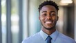 © Dylan - Young man smiling confidently in professional attire, conveying success and self-assurance in a modern workplace.