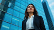 © NAD SANG PAP - confident young woman in business suit stands in front of modern glass building, exuding determination and ambition