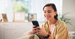 © Azee/peopleimages.com - Woman, happy and phone on sofa, relax and texting with funny meme in living room at apartment. Girl, person and smartphone with mobile app, comic video and smile on couch with social media in home