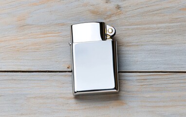 Poster - Close-up view of a chrome lighter on a rustic light brown wooden surface. The lighter is rectangular with a smooth, reflective surface.  Natural lighting enhances the metallic sheen