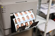 © New Africa - Modern printer with passport photos of man and woman indoors, closeup