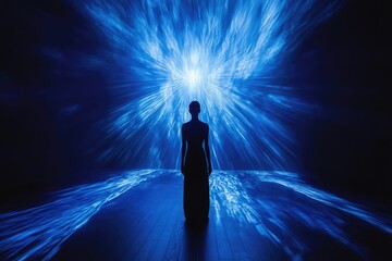 Wall Mural - Silhouette of a woman standing before a mesmerizing blue light projection resembling cosmic energy.