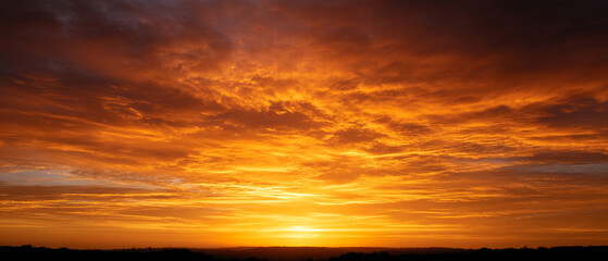 Poster - golden morning sky with sunrise creates stunning and vibrant scene, casting warm hues across horizon. clouds are illuminated in shades of orange and yellow, enhancing beauty