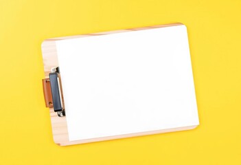 Wall Mural - Wooden clipboard with blank white paper and pen on yellow background, desk, background