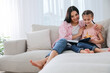 © New Africa - Mother and daughter with book on sofa in living room=