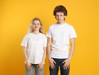 Wall Mural - young woman and man wearing blank white t-shirts on orange background. mockup for design