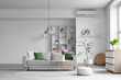© Pixel-Shot - Interior of light living room with grey sofa, shelf unit and plants