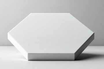 Poster - Modern white hexagonal object resting on a gray surface with subtle texture and shadows during indoor lighting