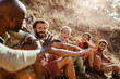 © Marko Geber - Group of friends resting and laughing during a sunny hiking adventure in the hills
