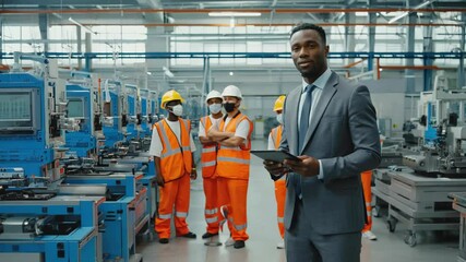 Poster - A man in a business suit stands in a factory, looking at his tablet.