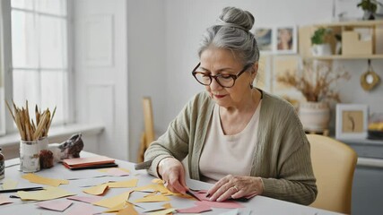 Poster - A person sits at a desk cutting out a piece of paper, possibly for crafting or DIY project.