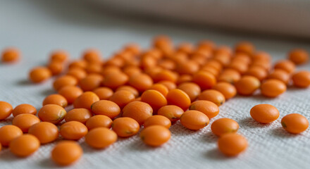 Poster - Pile of orange lentils seeds on a white surface showcasing their vibrant color and smooth texture creating a visually appealing and nutritious scene