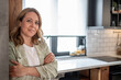 © Migma_Agency - Confident businesswoman smiling with arms crossed in modern kitchen