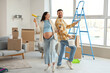© Pixel-Shot - Happy pregnant couple with paint tools during repair in their new house