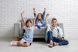 © Pixel-Shot - Happy little friends sitting on sofa near white brick wall