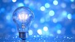 © Namdang - Bright Light Bulb Illuminating Blue Sparkling Background Effect