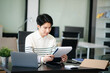 © laddawan - Young handsome man typing on tablet and laptop while sitting at the working table