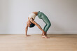 © Carlo Prearo - Young woman practicing yoga bridge pose on wooden floor