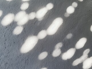 Poster - Abstract light patterns create a unique backdrop of soft shapes on a gray surface during bright daylight hours