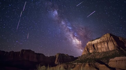 Majestic night sky with milky way galaxy and shooting stars over rugged mountain landscape.