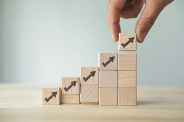 Poster - Wooden blocks forming an upward trending graph, hand placing final block, symbolizing growth, progress, and success in business strategy