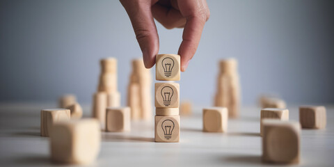 Poster - Hand placing wooden cube with lightbulb symbol onto stack, showcasing idea generation or problem-solving concept