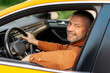 © Home-stock - Happy middle aged man working as taxi driver, sitting on drivers seat and smiling at camera through open window