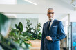 © Maria Vitkovska - Senior businessman wearing suit standing in modern office with plants