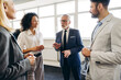 © Maria Vitkovska - Senior businessman leading meeting with diverse team in modern office