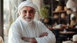 © CybStars - A joyful elderly man wearing traditional Arab attire, smiling warmly in a cozy cafe setting with beautiful decor in the background.