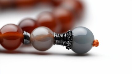 Poster - Close-up of prayer beads with orange, gray and brown spheres. Isolated on white background with blurred elements. Focus on texture and detail with bright lighting