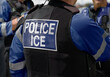 © Lawrey - Immigration and Customs Enforcement - Close-up of POLICE ICE marking on the back of a hi-visibility stab proof vest worn by a trio of police officers at the scene of an incident.