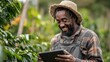 © Jannik - a happy Black farmer using a tablet at a coffee plantation