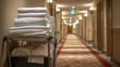 © dK - Neatly folded linens on hotel housekeeping cart in a clean, well-lit hallway