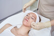 © elenavolf - Caucasian female receiving facial treatment in spa setting with gloved hands cleaning skin.