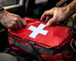 © Somkid - A person is opening a red first aid kit, revealing its contents, emphasizing preparedness and safety in emergency situations.