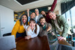 © CarlosBarquero - Multicultural coworkers laughing during a lively office meeting, showcasing teamwork, friendship, success, and a vibrant corporate atmosphere.
