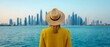 © Vibe Stock - Woman in yellow hat gazing at a city skyline by the water