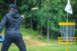 © Marika - disc golf player putting to yellow basket in summer