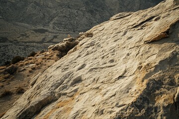 Aufkleber - A vast, textured rock face dominates the landscape, showcasing the beauty of natural erosion in a desert environment.