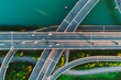 © Evgenii Bakhchev - Aerial view of multiple highways intersect above a calm river, surrounded by vibrant greenery.