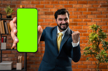 Holds green screen phone proudly, CEO advertises product in stylish office environment