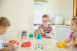 © Austockphoto - Three kids playing with colourful playdough inside