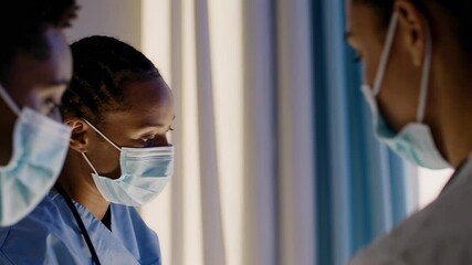 Aufkleber - Medical professionals wearing surgical masks are engaged in a serious discussion, potentially reviewing a patient's medical chart or discussing treatment strategies in a hospital setting