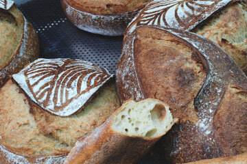 Poster - A display of bread with a variety of shapes and sizes. The bread is arranged on shelves and is ready to be sold.